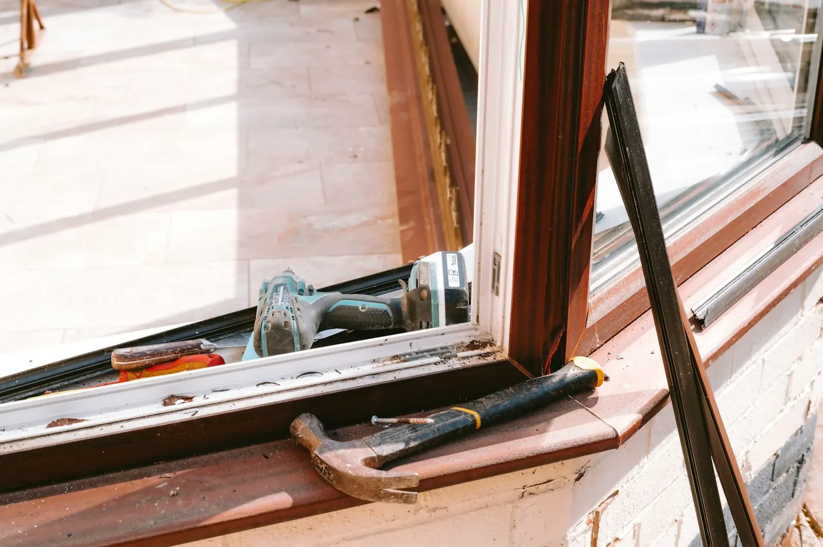 Hand tools and a cordless driver beside a window frame